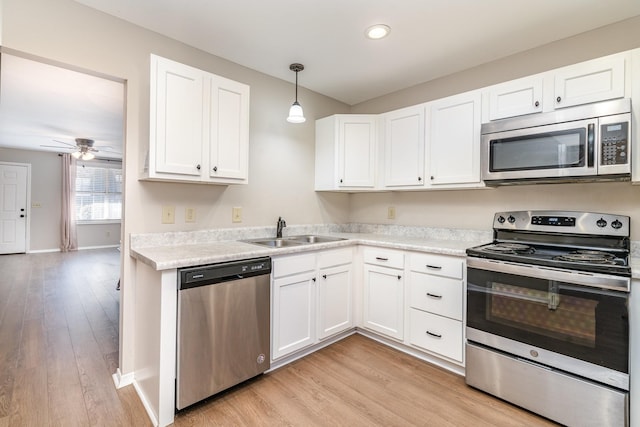 kitchen featuring pendant lighting, sink, stainless steel appliances, and white cabinets