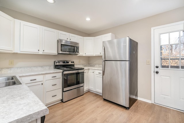 kitchen featuring stainless steel appliances, sink, light hardwood / wood-style flooring, and white cabinets