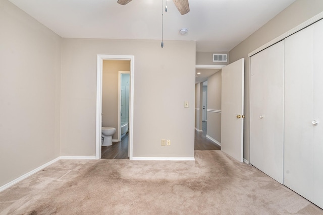 unfurnished bedroom with ceiling fan, ensuite bathroom, carpet flooring, and a closet