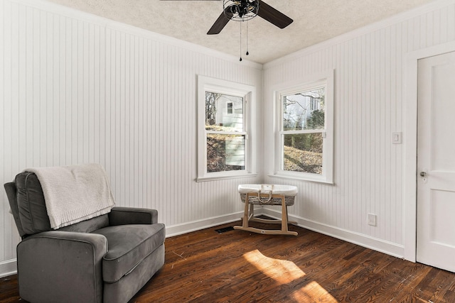 living area with crown molding, dark hardwood / wood-style floors, ceiling fan, and a textured ceiling