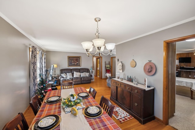 dining room with crown molding, light hardwood / wood-style floors, and an inviting chandelier