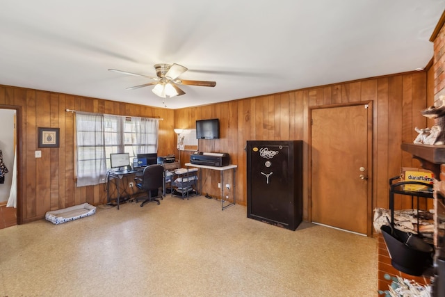 home office with ceiling fan and wood walls