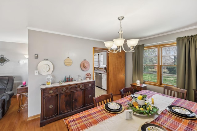 dining area featuring light hardwood / wood-style flooring, ornamental molding, and an inviting chandelier