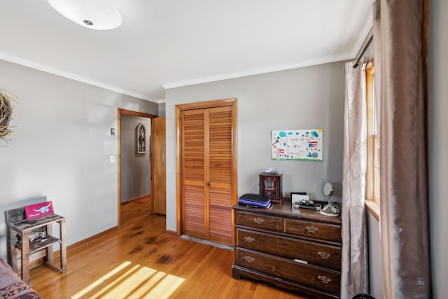 bedroom featuring ornamental molding, light hardwood / wood-style flooring, and a closet