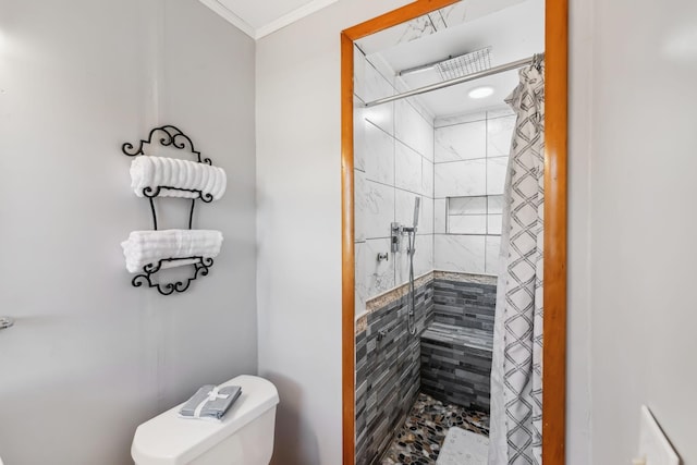 bathroom with tiled shower, toilet, and ornamental molding