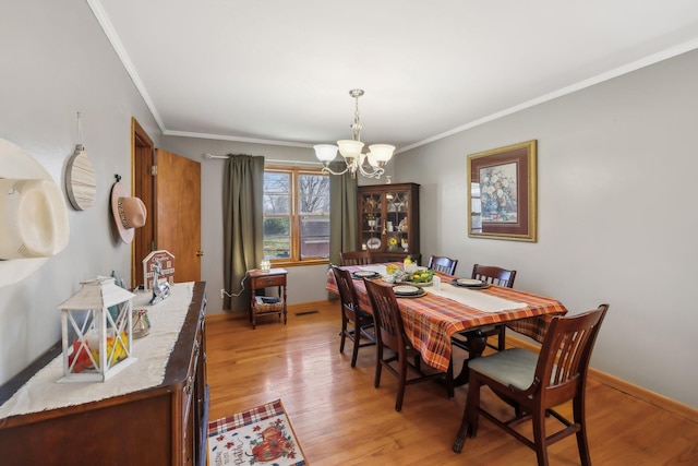 dining area featuring light hardwood / wood-style floors, crown molding, and a chandelier