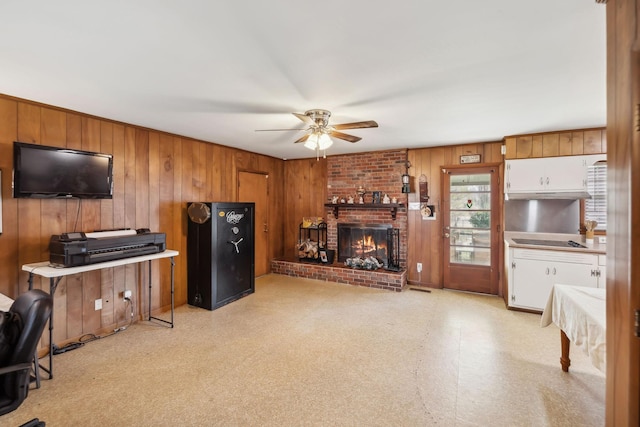 living room featuring ceiling fan, wood walls, and a fireplace