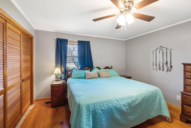 bedroom with hardwood / wood-style floors, ceiling fan, crown molding, and a closet