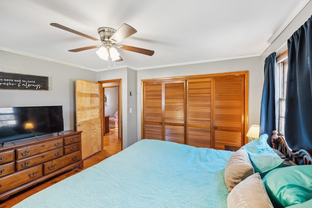 bedroom with a closet, ceiling fan, ornamental molding, and hardwood / wood-style flooring