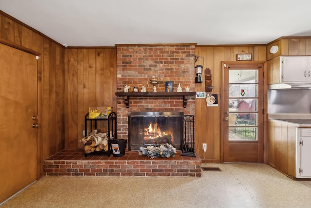 unfurnished living room with light colored carpet, wooden walls, and a brick fireplace