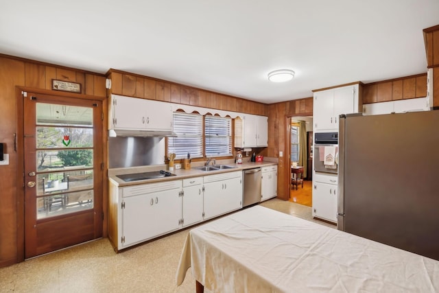 kitchen featuring white cabinetry, sink, wooden walls, and appliances with stainless steel finishes