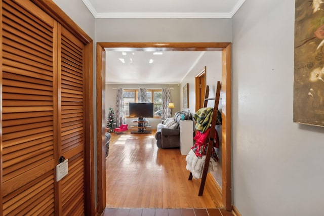 hallway with crown molding and light hardwood / wood-style flooring