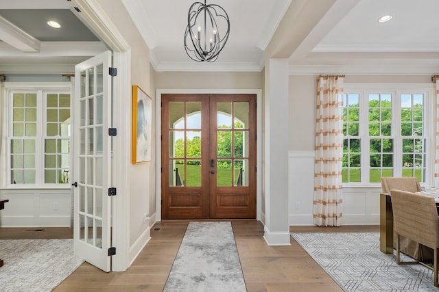 doorway featuring an inviting chandelier, ornamental molding, light hardwood / wood-style flooring, and french doors