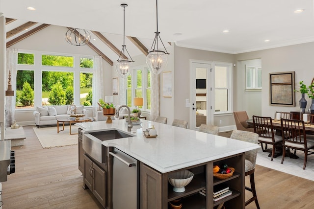 kitchen featuring stainless steel dishwasher, sink, pendant lighting, a center island with sink, and vaulted ceiling with beams