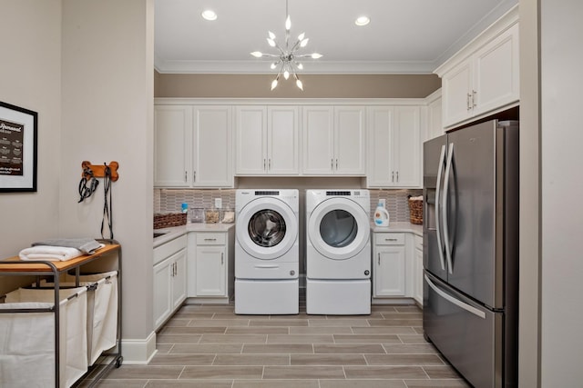 laundry area featuring ornamental molding, light hardwood / wood-style flooring, a chandelier, and independent washer and dryer