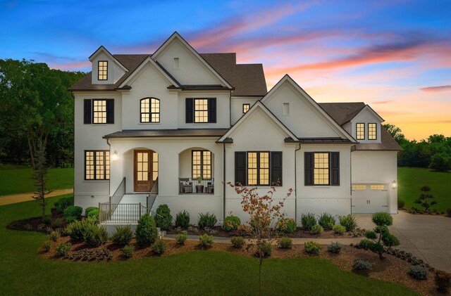 french country style house featuring a porch and a lawn