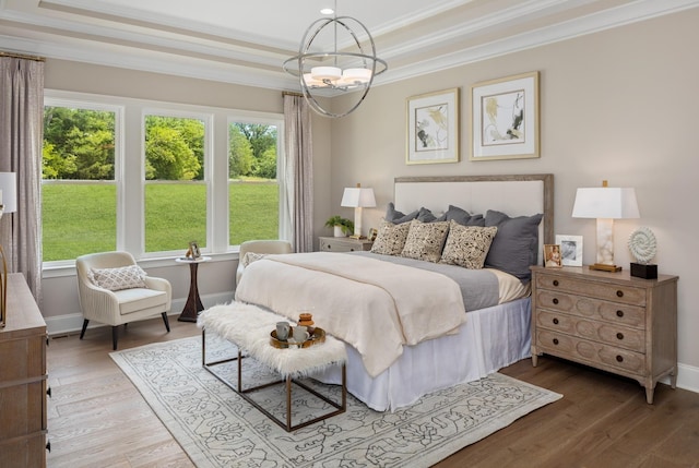 bedroom with hardwood / wood-style floors, ornamental molding, and an inviting chandelier