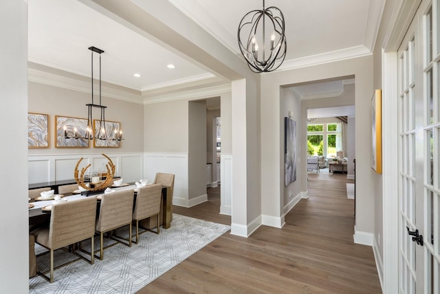 dining area with crown molding, a chandelier, and wood-type flooring