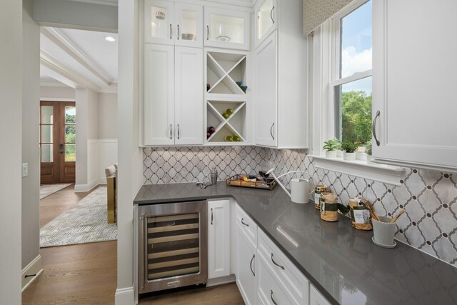 bar with white cabinetry, french doors, dark wood-type flooring, wine cooler, and ornamental molding