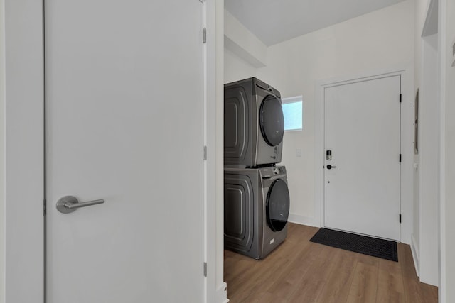 washroom with light hardwood / wood-style floors and stacked washer / dryer