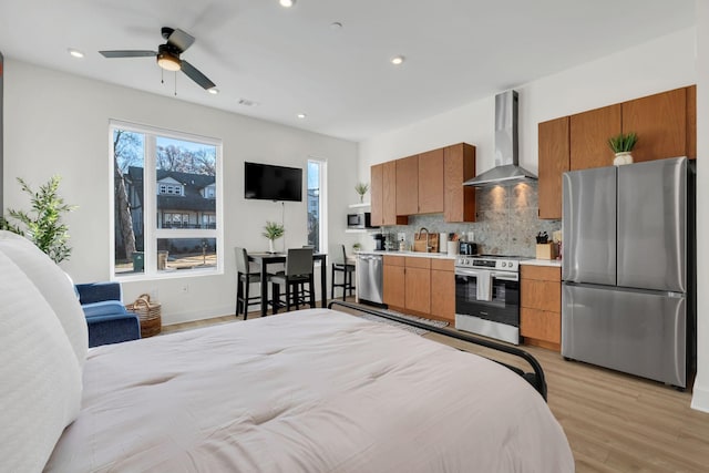 bedroom featuring light hardwood / wood-style flooring, stainless steel refrigerator, ceiling fan, and sink