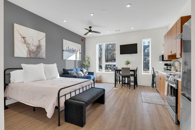 bedroom featuring ceiling fan, sink, and light wood-type flooring