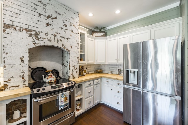 kitchen with dark wood-type flooring, appliances with stainless steel finishes, white cabinetry, backsplash, and wood counters