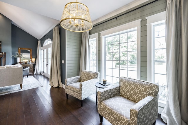 sitting room featuring wood walls, vaulted ceiling, dark wood-type flooring, and an inviting chandelier