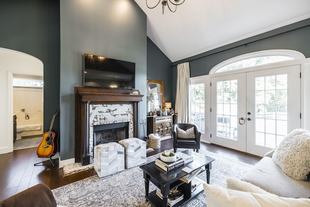 living room featuring french doors, dark hardwood / wood-style floors, a tiled fireplace, and high vaulted ceiling