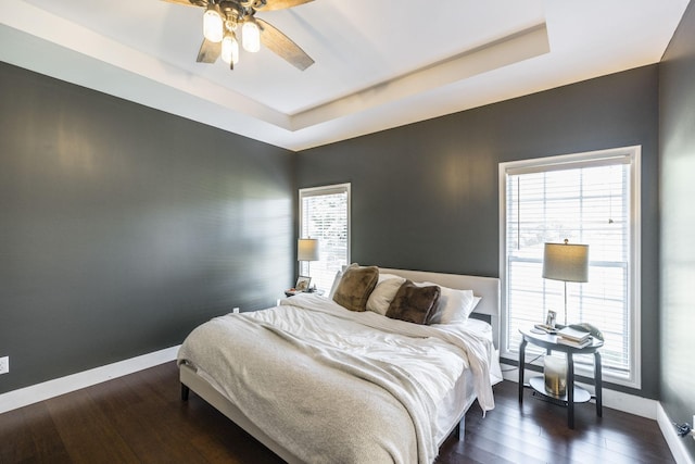 bedroom featuring a raised ceiling, ceiling fan, and dark hardwood / wood-style floors