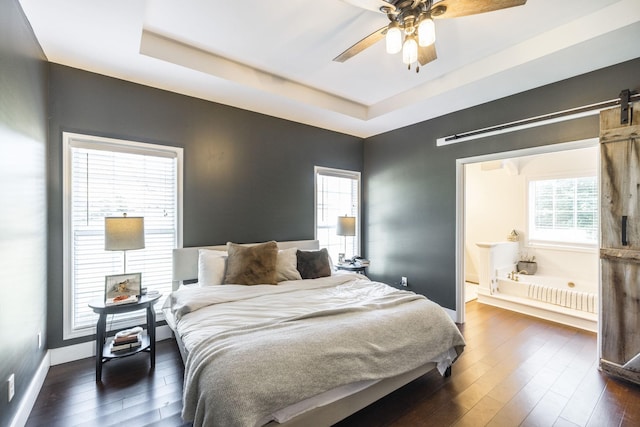 bedroom with ceiling fan, dark hardwood / wood-style flooring, and a tray ceiling