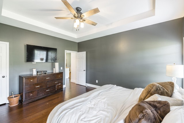 bedroom with a tray ceiling, dark hardwood / wood-style floors, and ceiling fan