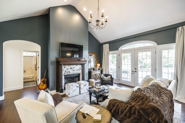 living room with dark wood-type flooring, high vaulted ceiling, an inviting chandelier, french doors, and a fireplace