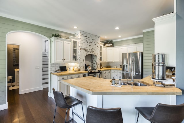 kitchen with a breakfast bar, wood counters, white cabinets, dark hardwood / wood-style flooring, and stainless steel appliances