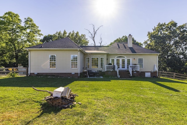 back of property with a lawn, a wooden deck, and french doors