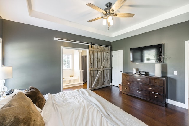 bedroom featuring dark wood-type flooring, radiator, a raised ceiling, ceiling fan, and a barn door