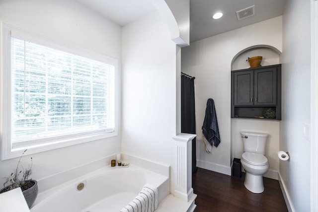 bathroom featuring hardwood / wood-style flooring, toilet, and plus walk in shower