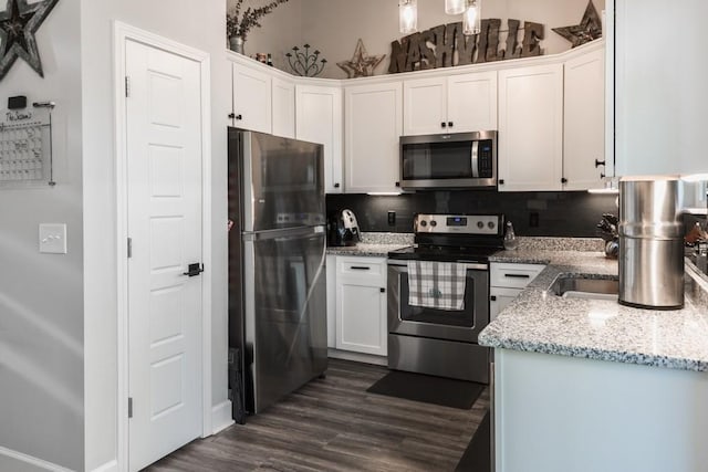 kitchen featuring stainless steel appliances, white cabinets, tasteful backsplash, light stone countertops, and dark hardwood / wood-style floors