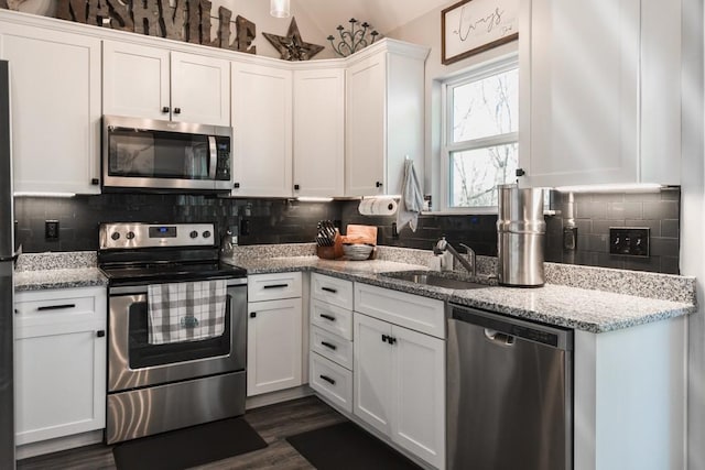 kitchen featuring stainless steel appliances, decorative backsplash, white cabinetry, and sink