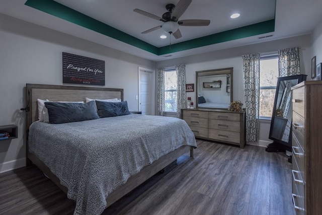 bedroom with a raised ceiling, ceiling fan, and dark hardwood / wood-style flooring