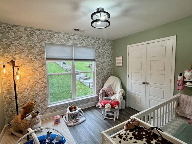 unfurnished bedroom featuring a closet, a crib, and dark hardwood / wood-style floors