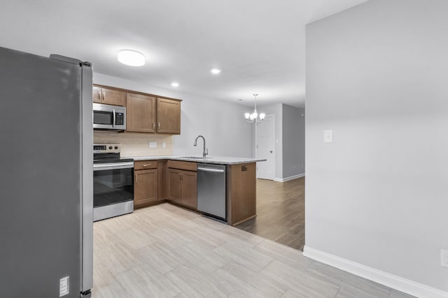 kitchen with pendant lighting, backsplash, sink, kitchen peninsula, and stainless steel appliances