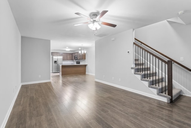 unfurnished living room with dark wood-type flooring and ceiling fan with notable chandelier