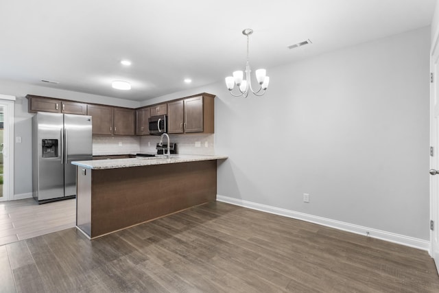 kitchen with hardwood / wood-style floors, an inviting chandelier, kitchen peninsula, dark brown cabinetry, and stainless steel appliances