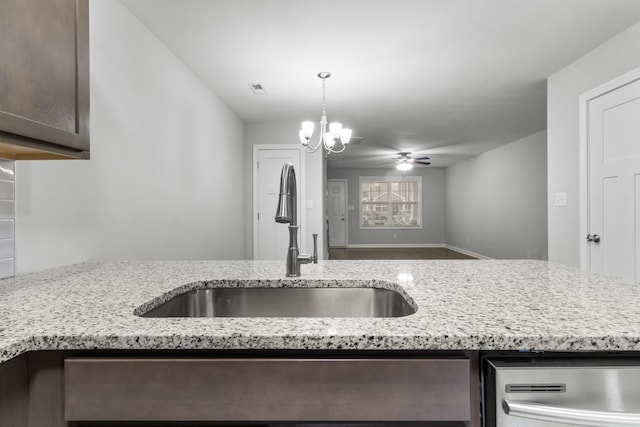 kitchen featuring dark brown cabinetry, sink, light stone counters, stainless steel dishwasher, and ceiling fan with notable chandelier