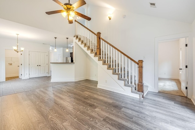 unfurnished living room featuring vaulted ceiling, wood-type flooring, and ceiling fan with notable chandelier