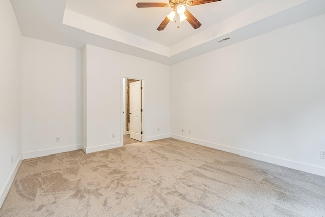 carpeted empty room featuring a raised ceiling and ceiling fan