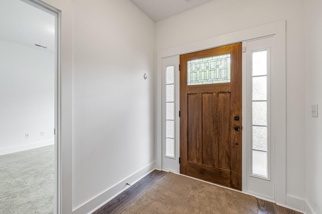 foyer entrance featuring dark carpet and a wealth of natural light