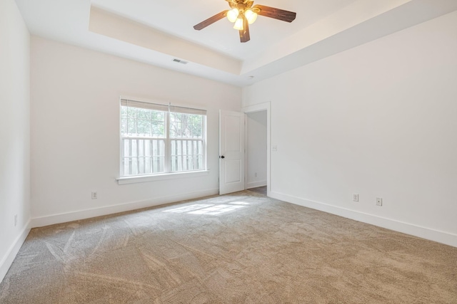 carpeted spare room featuring ceiling fan and a raised ceiling