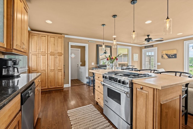 kitchen with appliances with stainless steel finishes, ceiling fan, dark wood-type flooring, a kitchen island, and hanging light fixtures